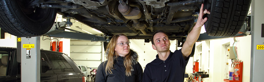 Mechanic working under a car on a lift at Aðalverkstæðið